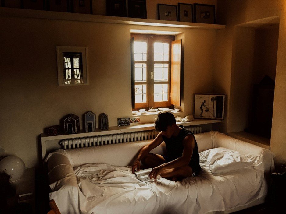 Student sitting on a bed reading a book, symbolizing life in student accommodation in Poland.