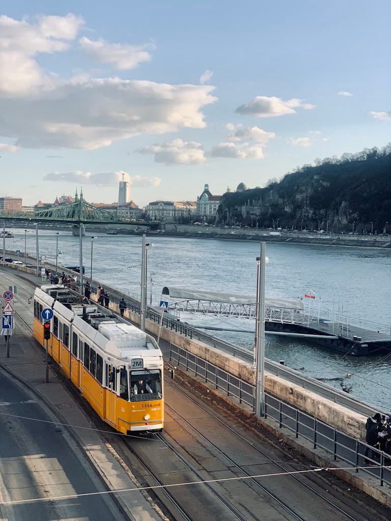 Yellow and White Tram on Tramline Near a Body of Water