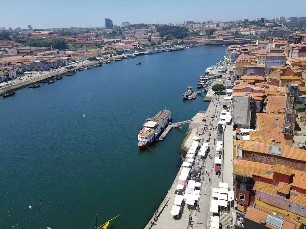 Stunning aerial view of Porto, Portugal with boats docked along the riverside on a sunny day.