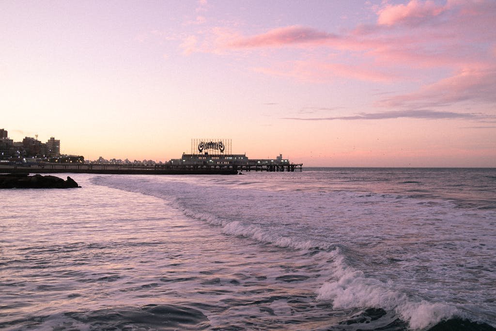 Beautiful sunset view at Mar del Plata beach, Argentina with ocean waves and pier silhouette. There you can buy a home for under 100,000 dollars.