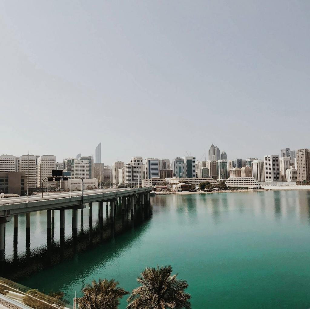 Explore the dynamic cityscape of Abu Dhabi featuring a modern bridge and skyline over tranquil waters.