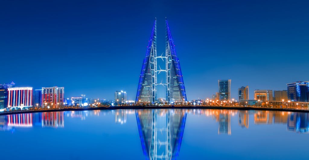 Stunning night view of Bahrain World Trade Center with clear water reflections and modern skyline.