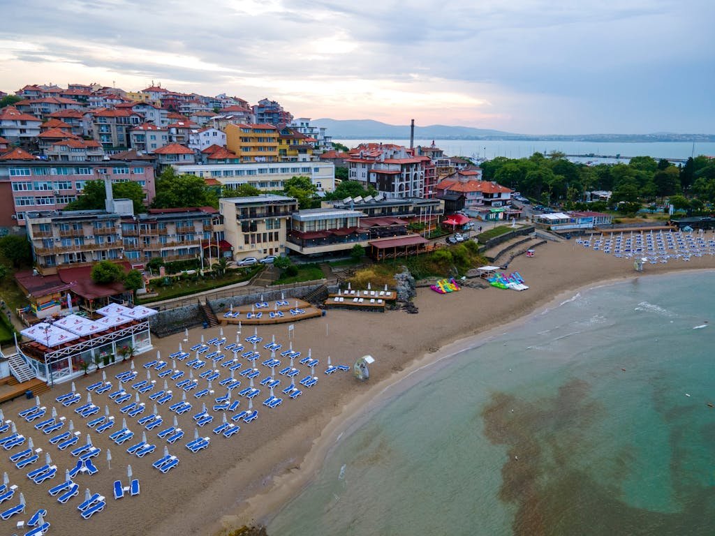 Aerial view of Sozopol's beach with sunbeds, buildings, and coastal scenery in Bulgaria.