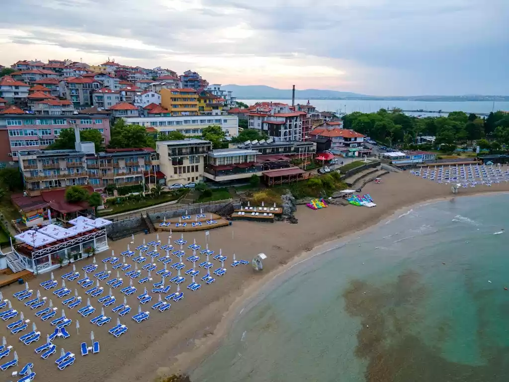 Aerial view of Sozopol's beach with sunbeds, buildings, and coastal scenery in Bulgaria.