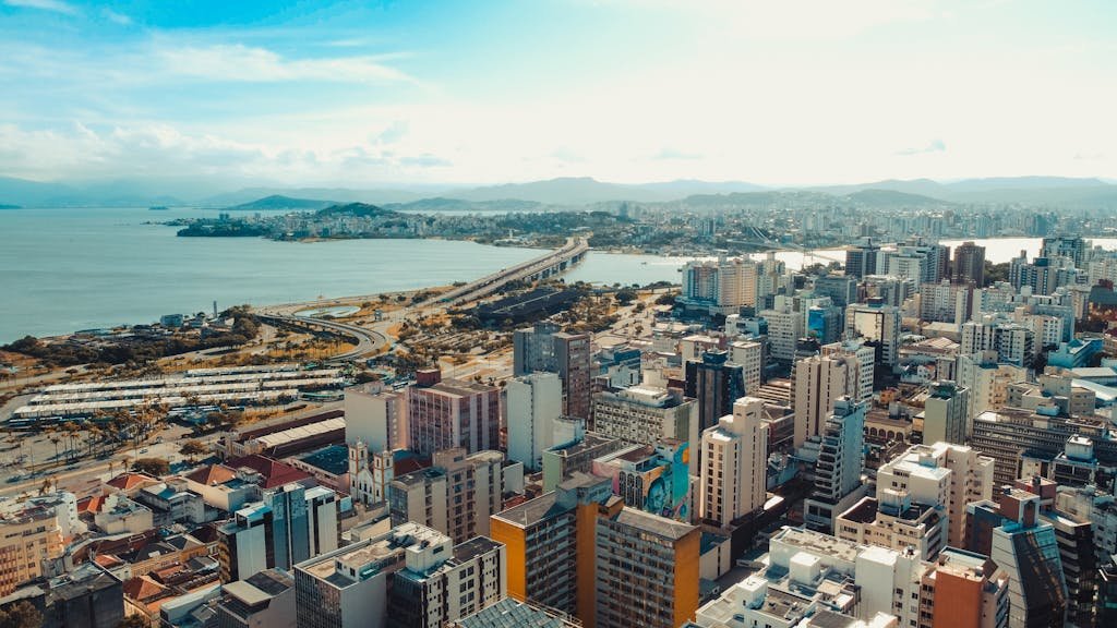 Panoramic aerial view of Florianópolis cityscape with coastline and vibrant city buildings.