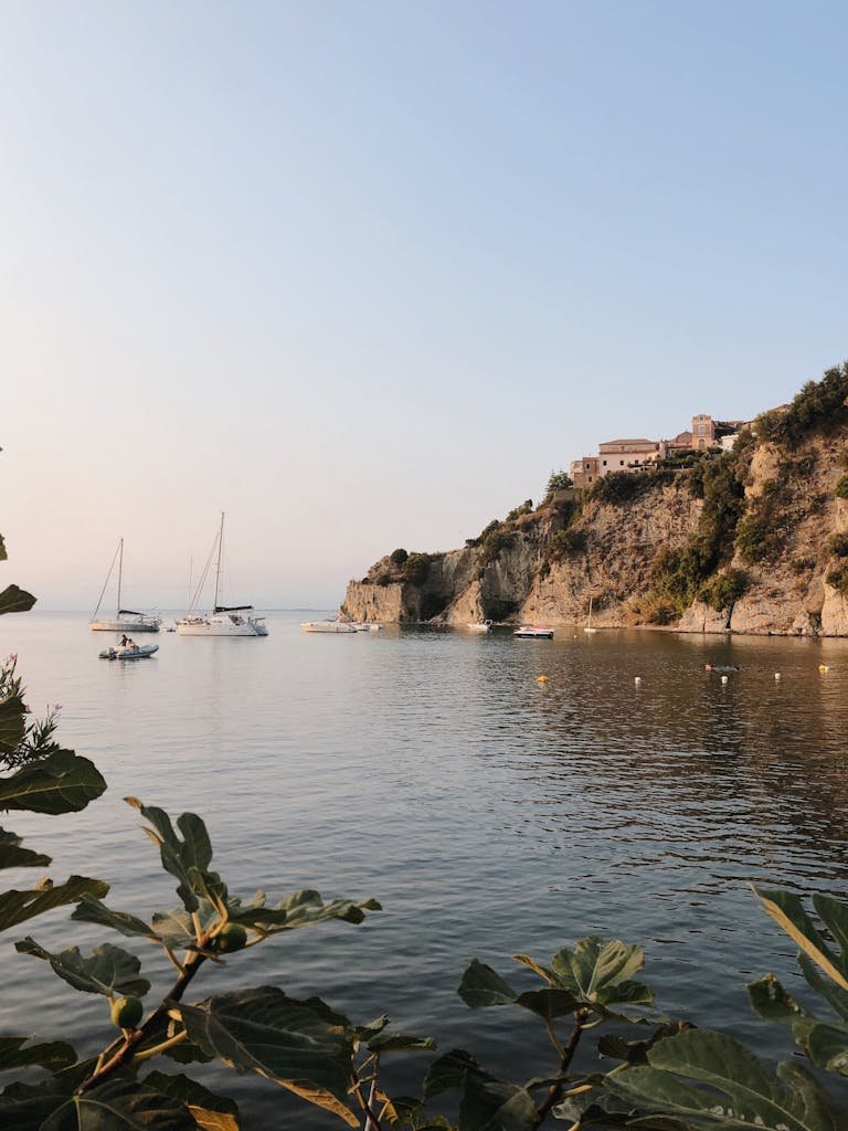 Beautiful view of Agropoli's cliffs and boats on a calm sea during sunrise.