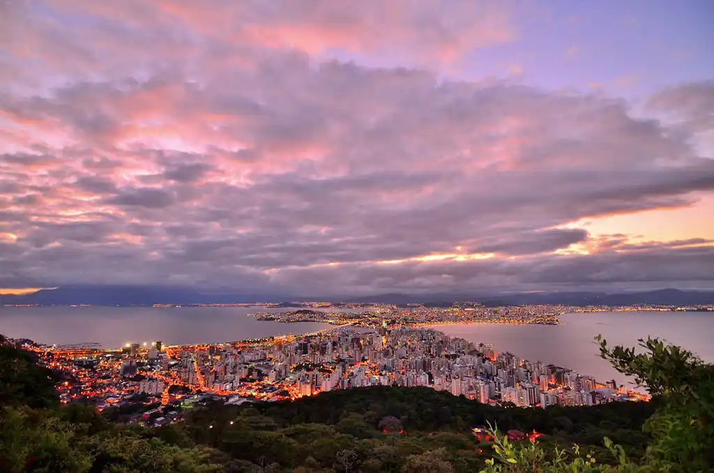 Breathtaking view of Florianópolis, Brazil at sunset, showcasing cityscape and ocean under vibrant sky.